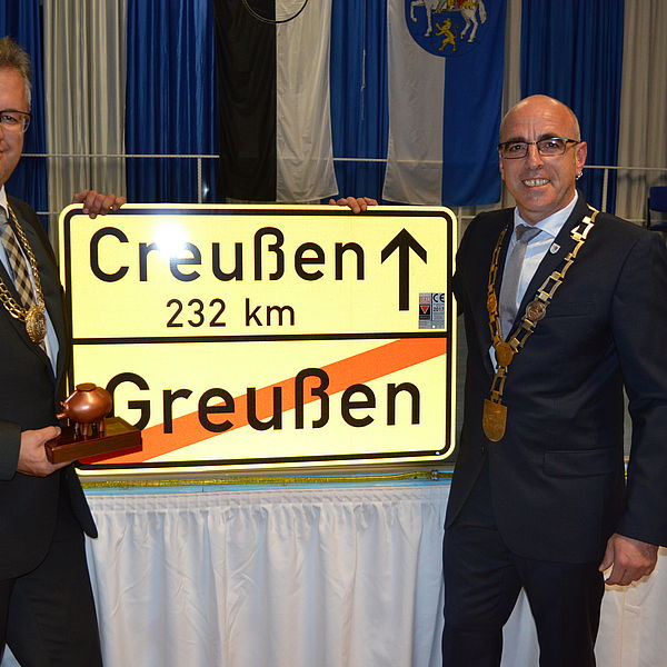 Die beiden Bürgermeister Martin Dannhäußer und René Hartnauer mit einem Ortsschild Greußen - Creußen, 232 Kilometer